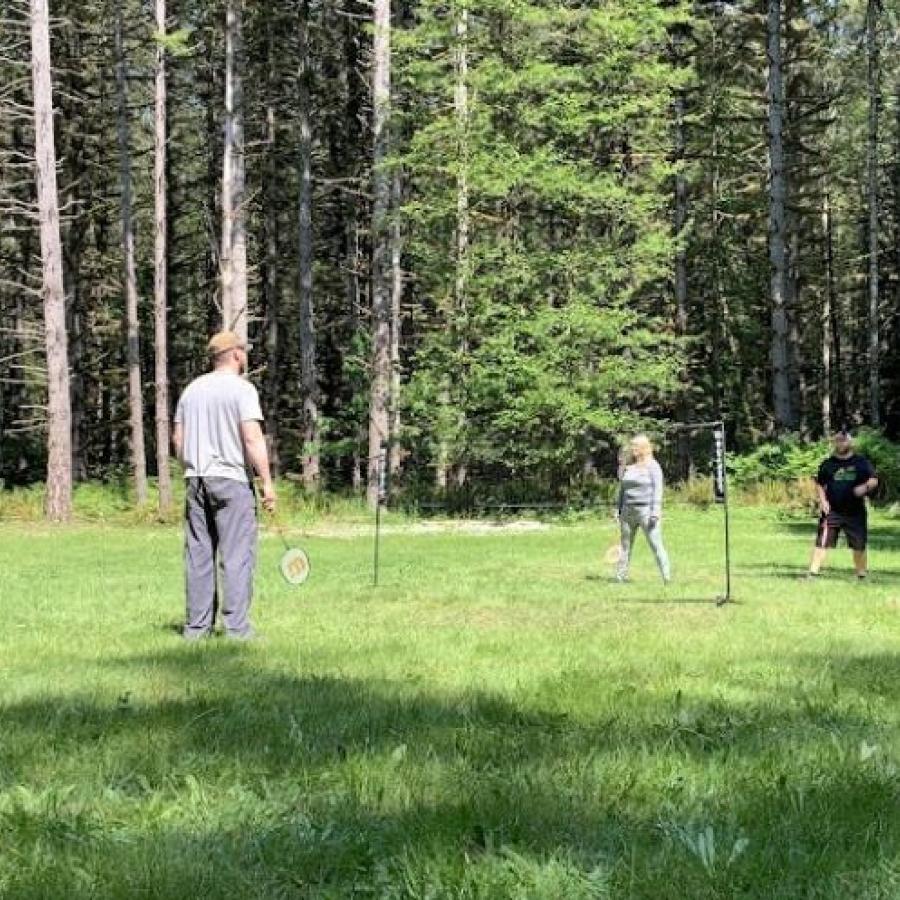 four visitors playing a game of badminton on grassy field