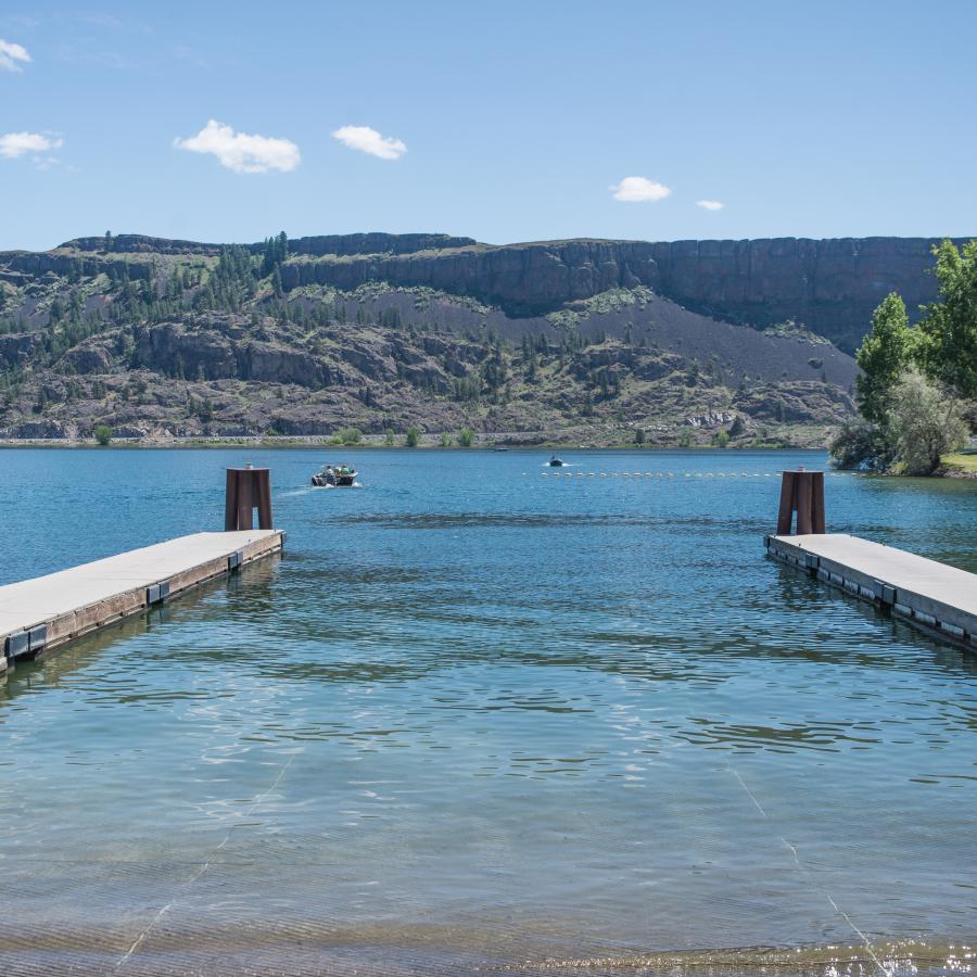 Wide boat launch, lined with two docks and hillside in the background