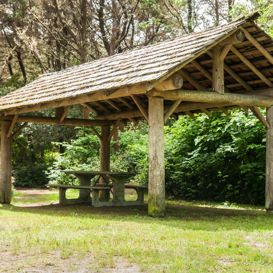 rustic round wood picnic shelter with tables underneath