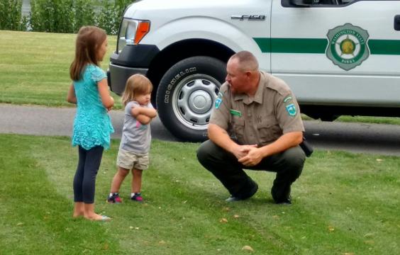 Park ranger talking with children in front of truck 