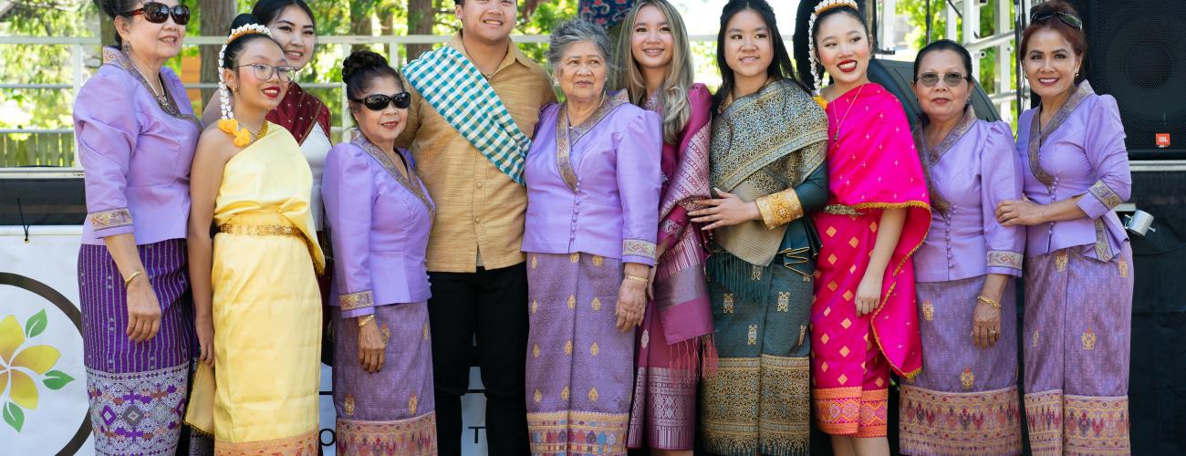 A group of people from the United Communities of Laos dressed in traditional clothing standing in front of the stage in Lake Sammamish State Park
