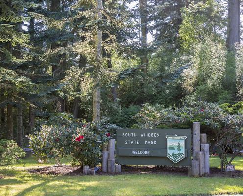 Welcome sign with trees and flowers