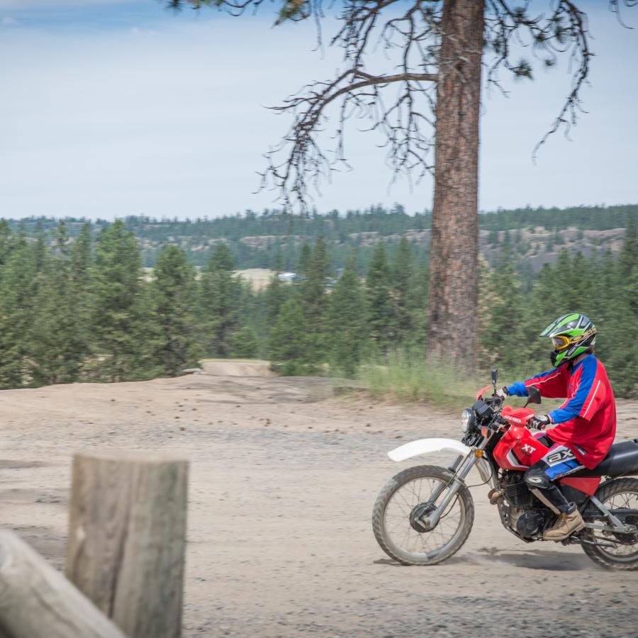A visitor rides a dirt bike along a bluff in the Off Road Vehicle area.