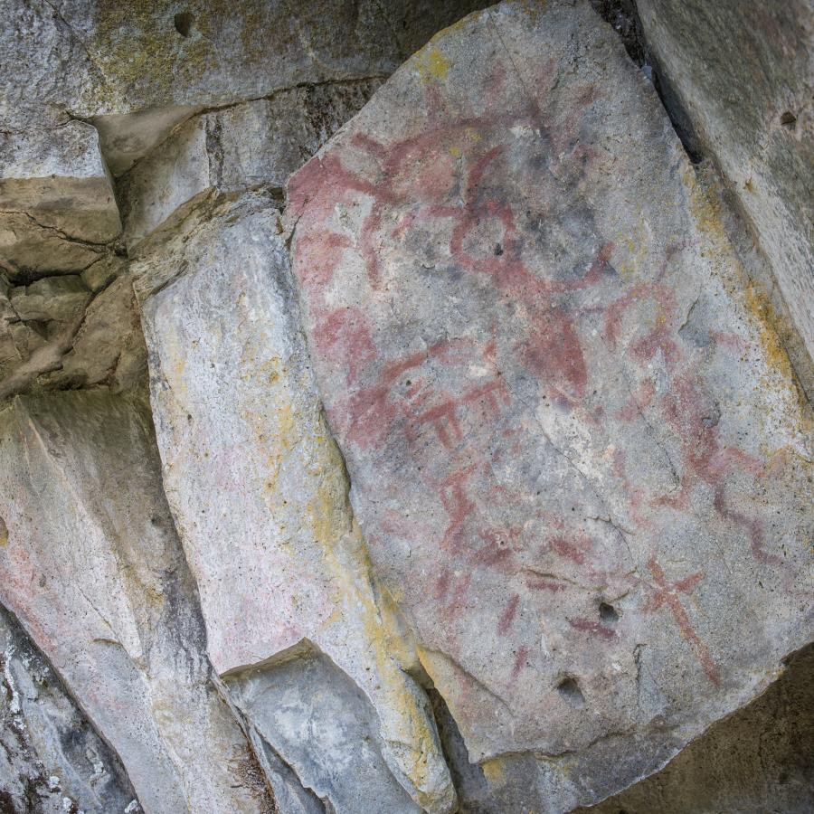 Historic Native American drawings in red on a rock.