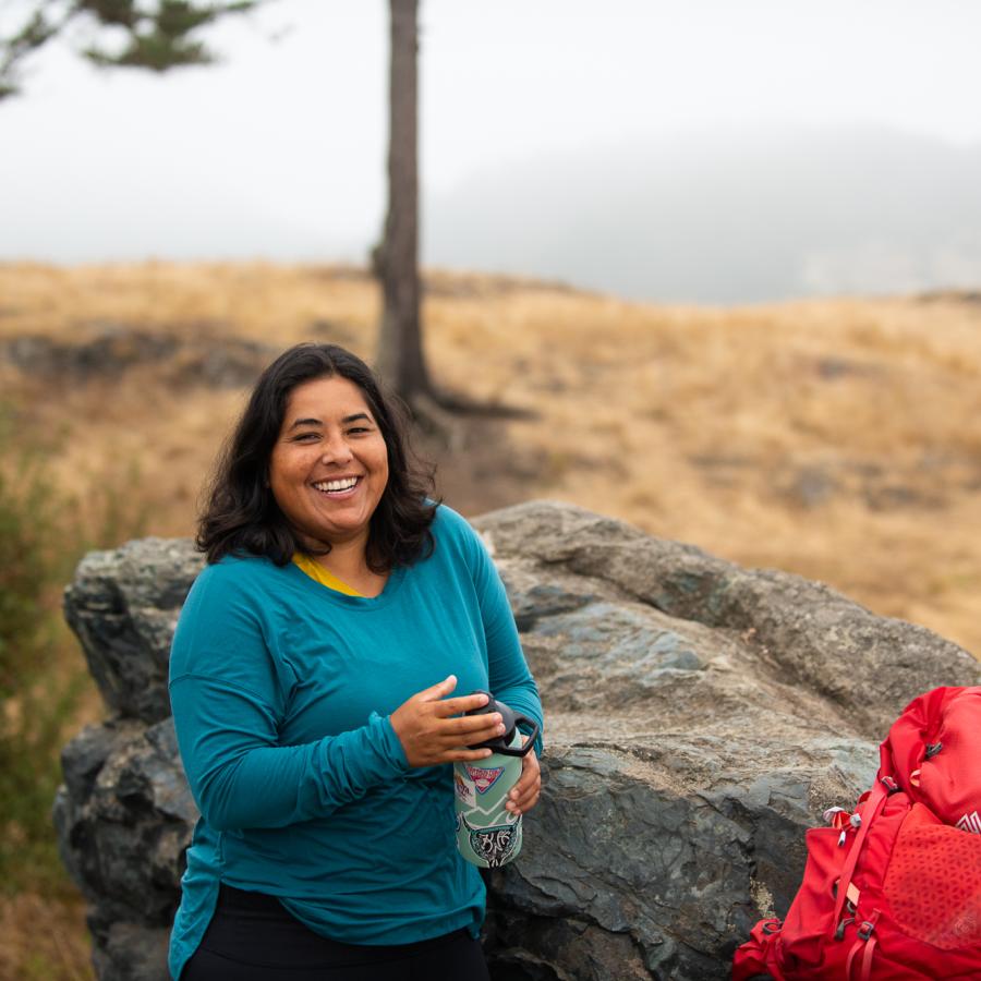 Hiker smiling with water and backpack.
